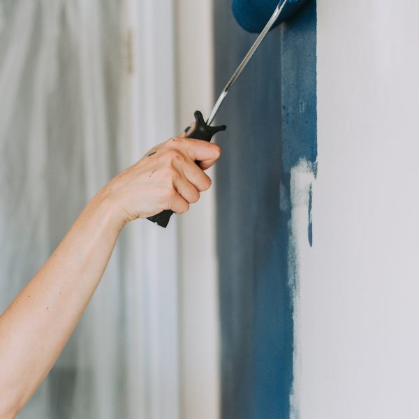 A closeup shot of a person using paint rollers with the color blue